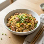 Bowl of chicken fried rice with golden chicken, egg, peas, and green onions for a weeknight dinner