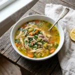 Bowl of easy chicken soup with golden broth, shredded chicken, and carrots on a rustic wooden table