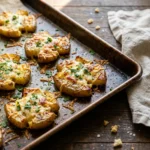 Golden crispy smashed potatoes with Parmesan and parsley on a sheet pan, fresh from the oven